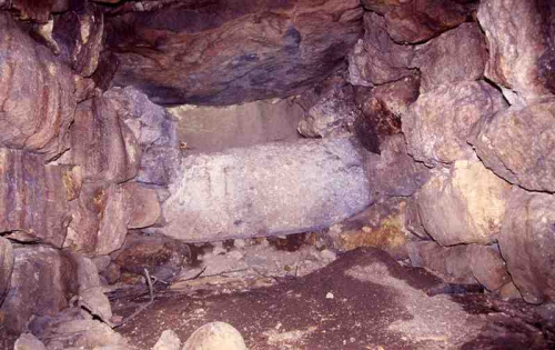 古墳の石室内部の写真です。積み上げられた石と石室奥の岩が写っています。