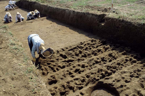 発掘作業員がスコップなどの道具を使って遺構の中に埋まった土を掘っている様子