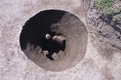 井戸として使われていた円形の大きな穴の中に、出土した土器がそのままの状態で残されている写真