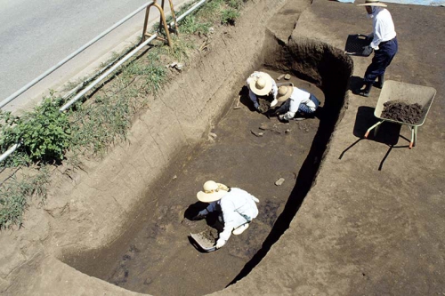 発掘作業員がスコップなどの道具を使って遺構の中に埋まった土を掘っている様子